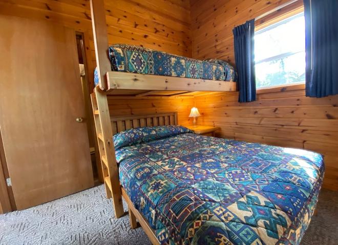 Bedroom with a full size bed, with a twin lofted above it, and an ensuite bathroom.