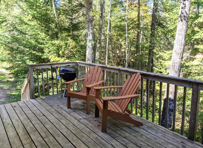 Deck area with chairs and charcoal grill.