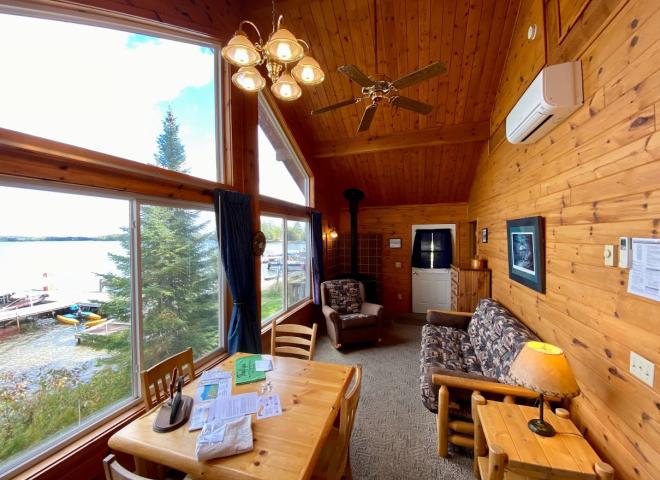 Living area with views of Lake Vermilion, kitchen table, futon, chair, and wood burning fireplace.