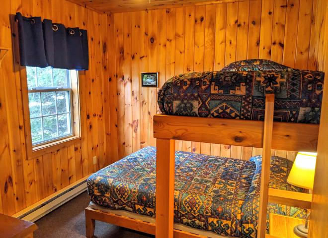 Bedroom with a full size bed and a twin lofted above it.