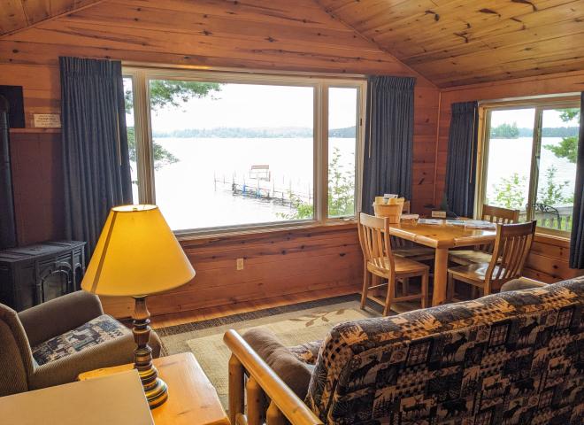 Living area with a futon, chair, gas fireplace, kitchen table, and a picture window capturing Lake Vermilion.