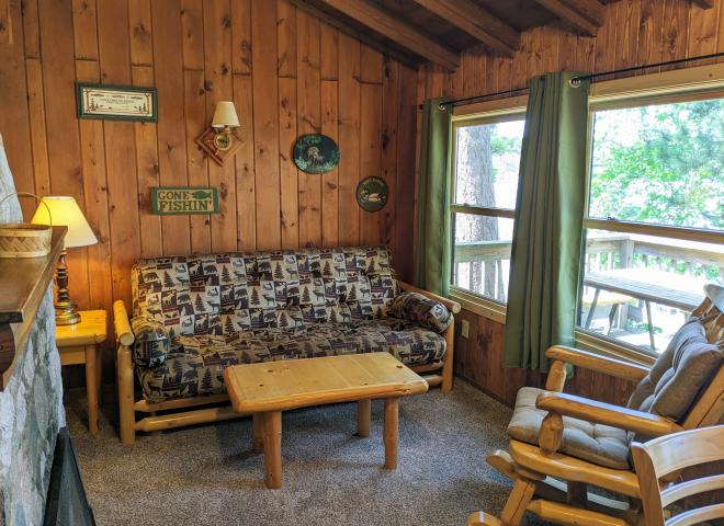 Living room with futon, chair, and wood burning fireplace.