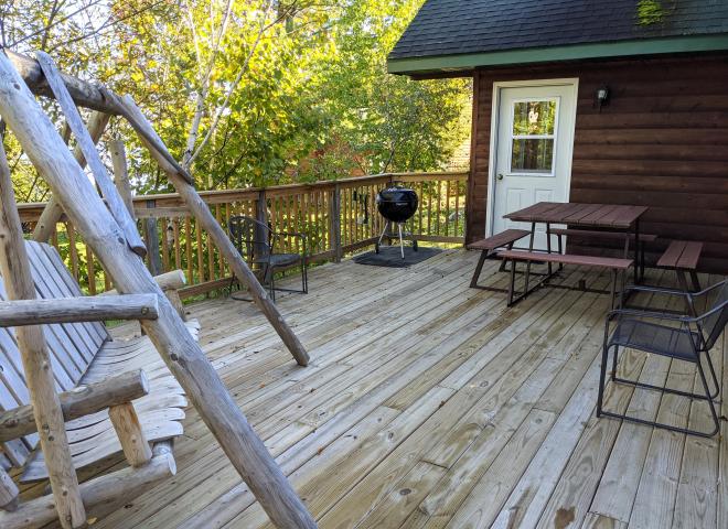 Deck area with swinging bench, picnic table, and charcoal grill.