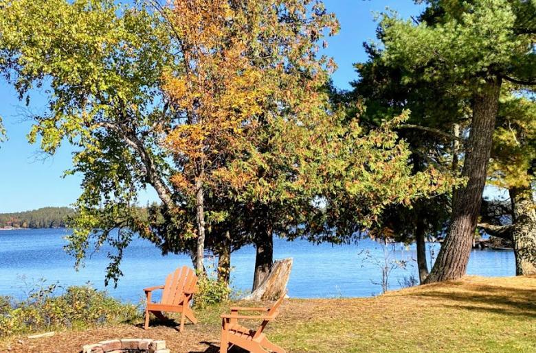 Private yard with shoreline, picnic table, and firepit.