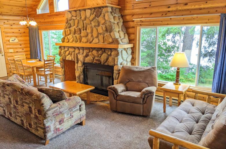 Living area with couch, recliner, futon, and wood burning fireplace.