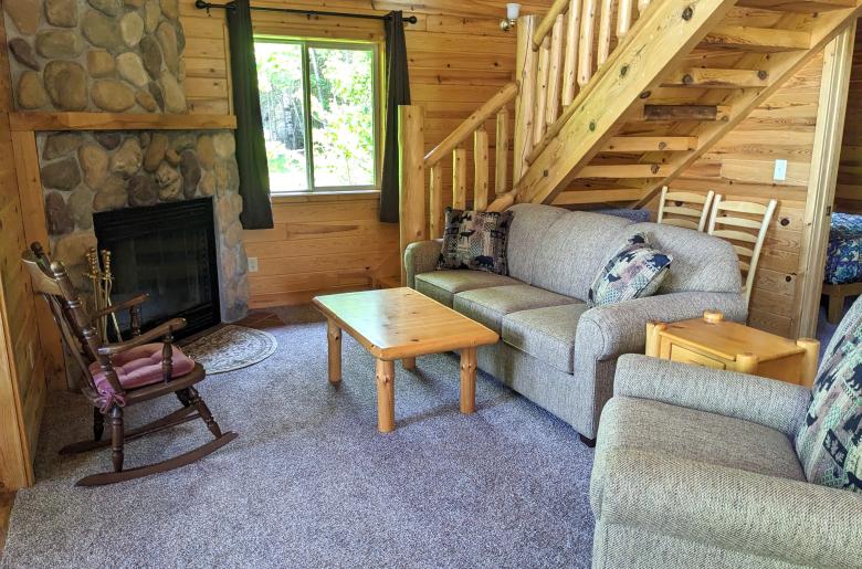 Living room with couch, recliner, and wood burning fireplace.