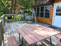 Deck area with a picnic table, charcoal grill, and swinging bench.
