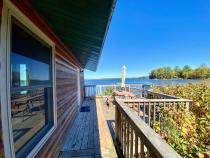 Deck area overlooking the lake and beach with picnic table and charcoal grill.