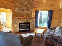 Living room with couch, loveseat, and wood burning fireplace.
